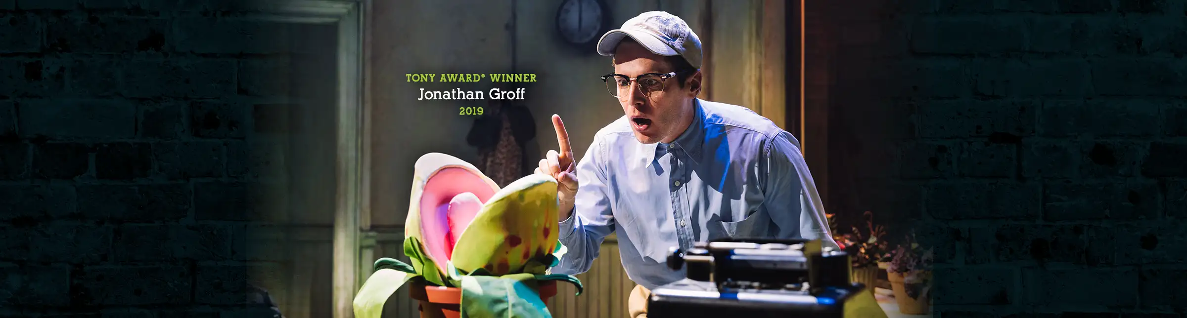 Tony Award winner Jonathan Groff performing as Seymour in the 2019 Broadway revival of Little Shop of Horrors, interacting with the Audrey II plant.